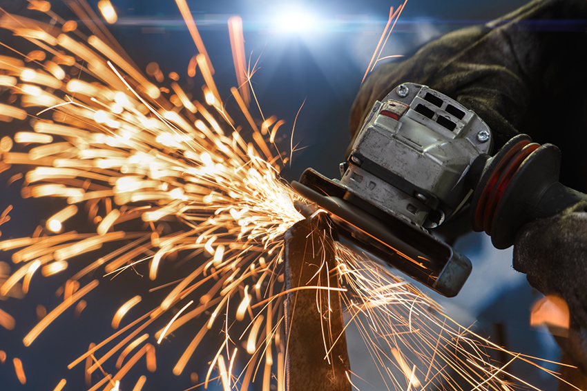 A close up of an angle grinder in action on a piece of metal, creating lots of sparks.
