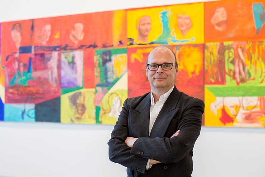 Professor Kris Gledhill standing against wall. 