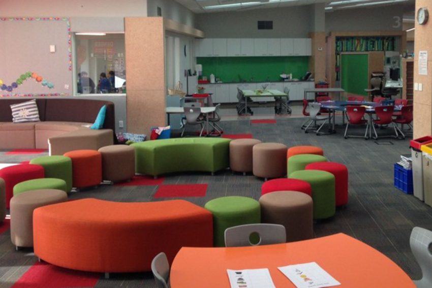 A photo of a colourful open plan classroom, with a large area that has different arrangements of seating and activity spaces.