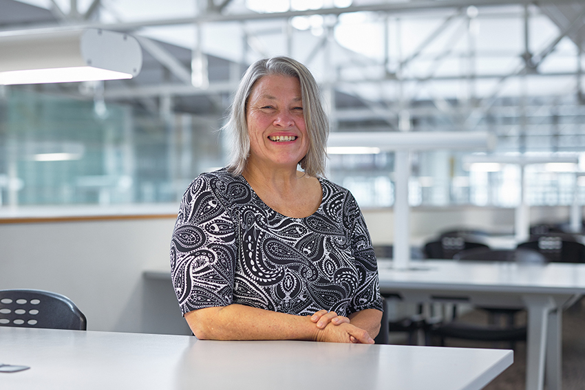 Sharon Harvey smiling in an open student study area inside at AUT.
