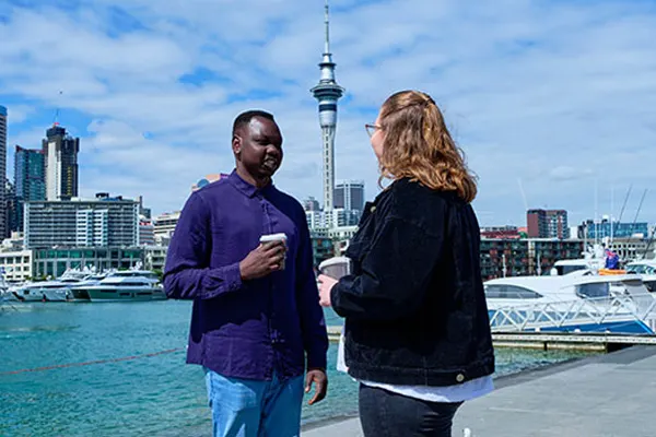 International students chatting with Sky tower and boats in background